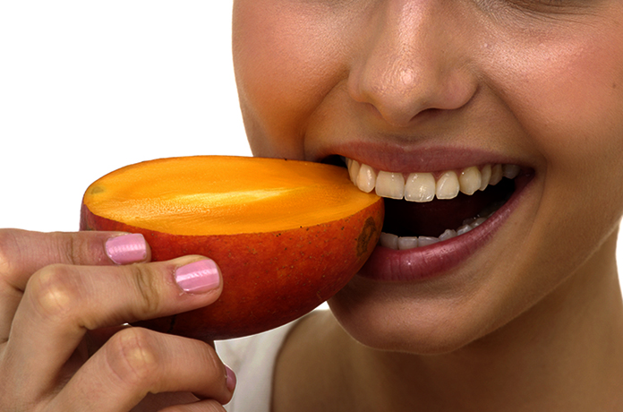 Женщина кушает манго