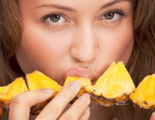 Девушка кушает ананас